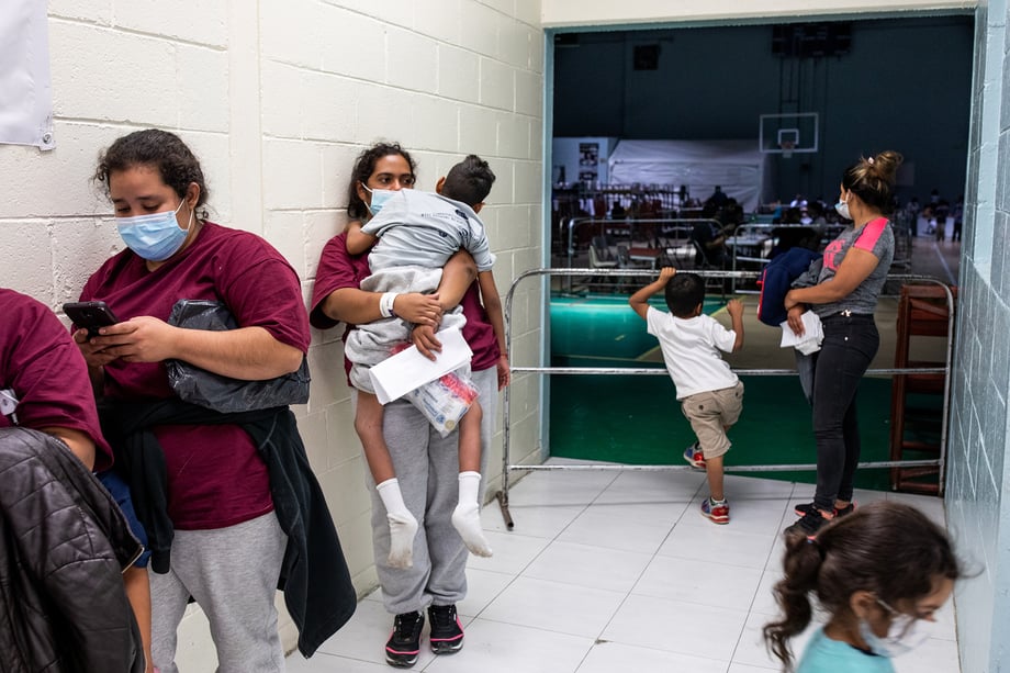 Woman in maroon shirts and grey sweatpants wait with their kids at the Kiki Romero shelter shot by Lisette Poole for National Geographic Magazine