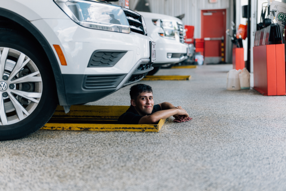 Mechanic peeking out from under a car shot by Abigail Bobo for Caliber Collision