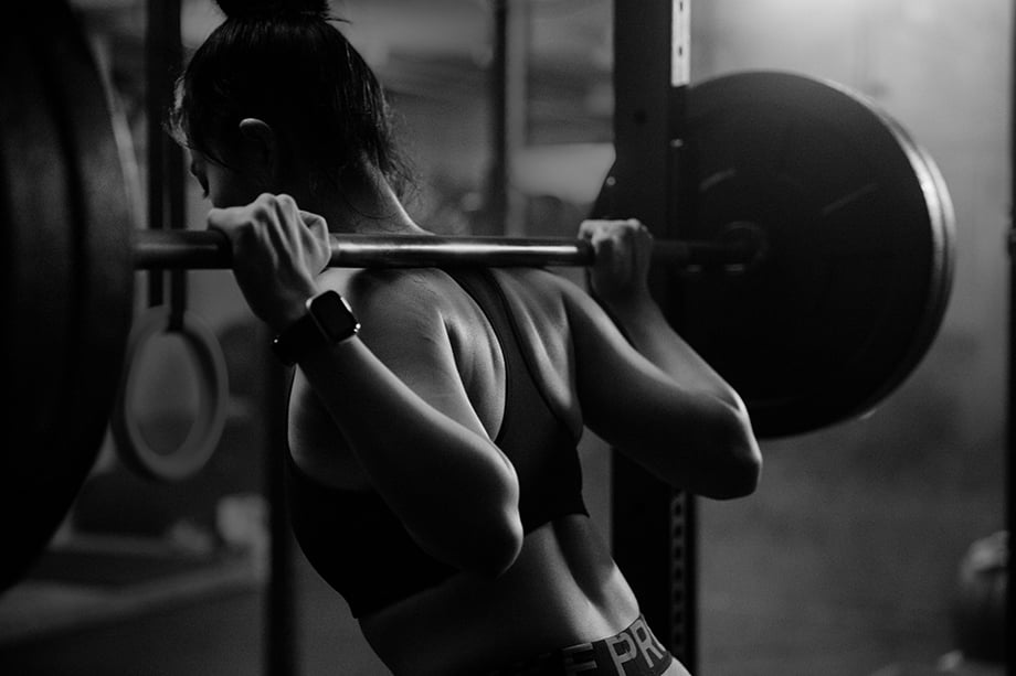 Image of Carrie Xu lifting weights taken from behind. Photographed by Albert Law. 