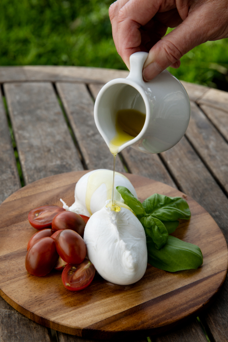 Olive oil being poured over fresh mozzarella, cherry tomatoes and basil shot by Angela DeCenzo for National Geographic Traveller Food magazine