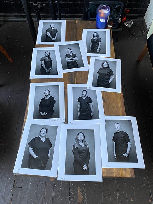 A behind-the-scenes look at Angelo Merendino's printed portraits of nurses on a table. 