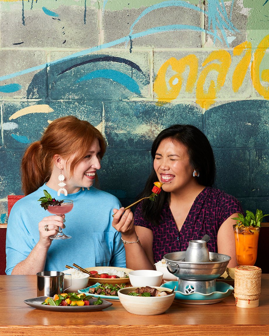 Two women enjoy drinks and food in front of mural at Talat Market for Atlanta magazine 13 best restaurants shot by Bailey Garrot