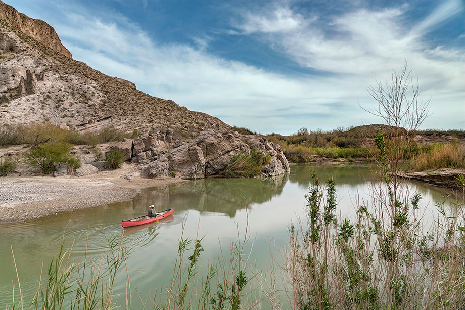 A man paddles back to Mexico across the Rio Grande river after selling souvenirs to tourists in Big Bend National Park, Texas. Photography by Bob Rives. 