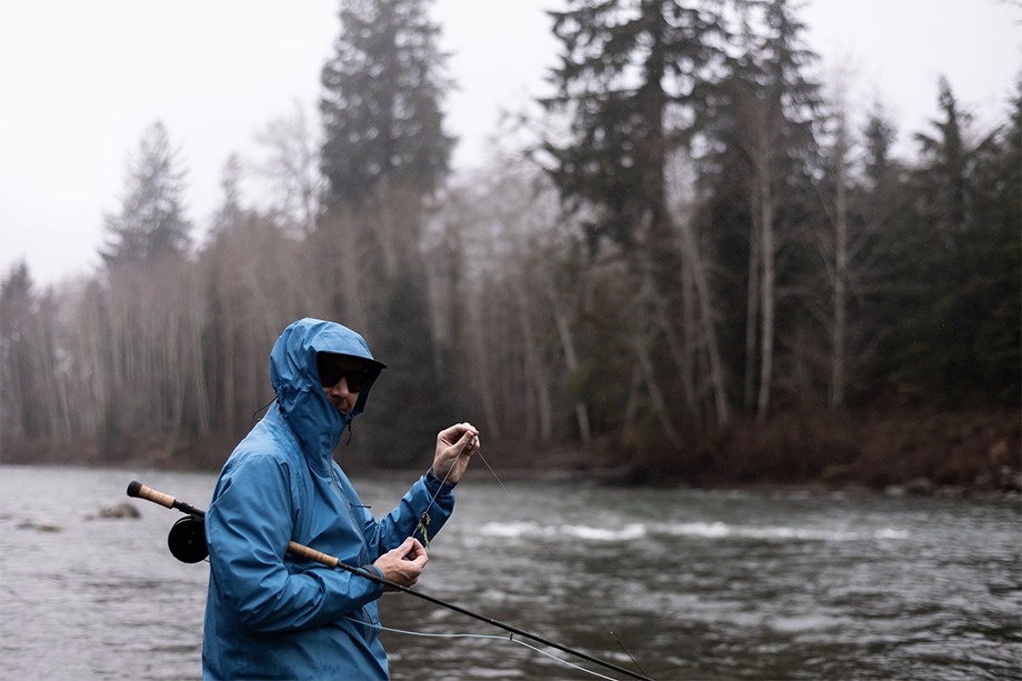 Man in a raincoat holds a fishing rod. Photographed by Cameron Karsten for Patagonia. 