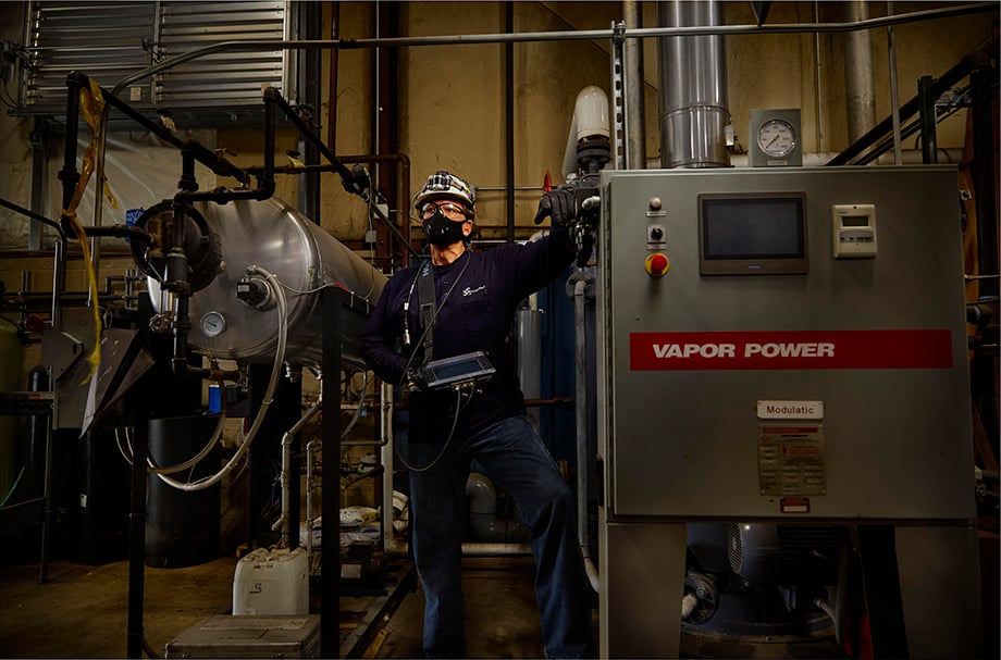 Portrait of a NovaSpect employee at work next to industrial equipment. Photographed by Darren Hauck.