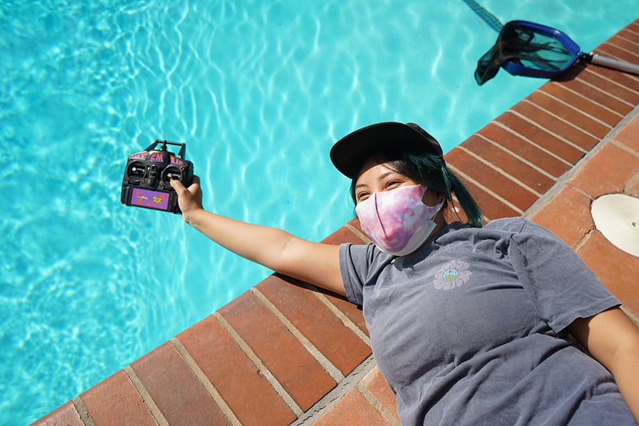 Emily Malan holds the remote control for the small yatch in the pool.
