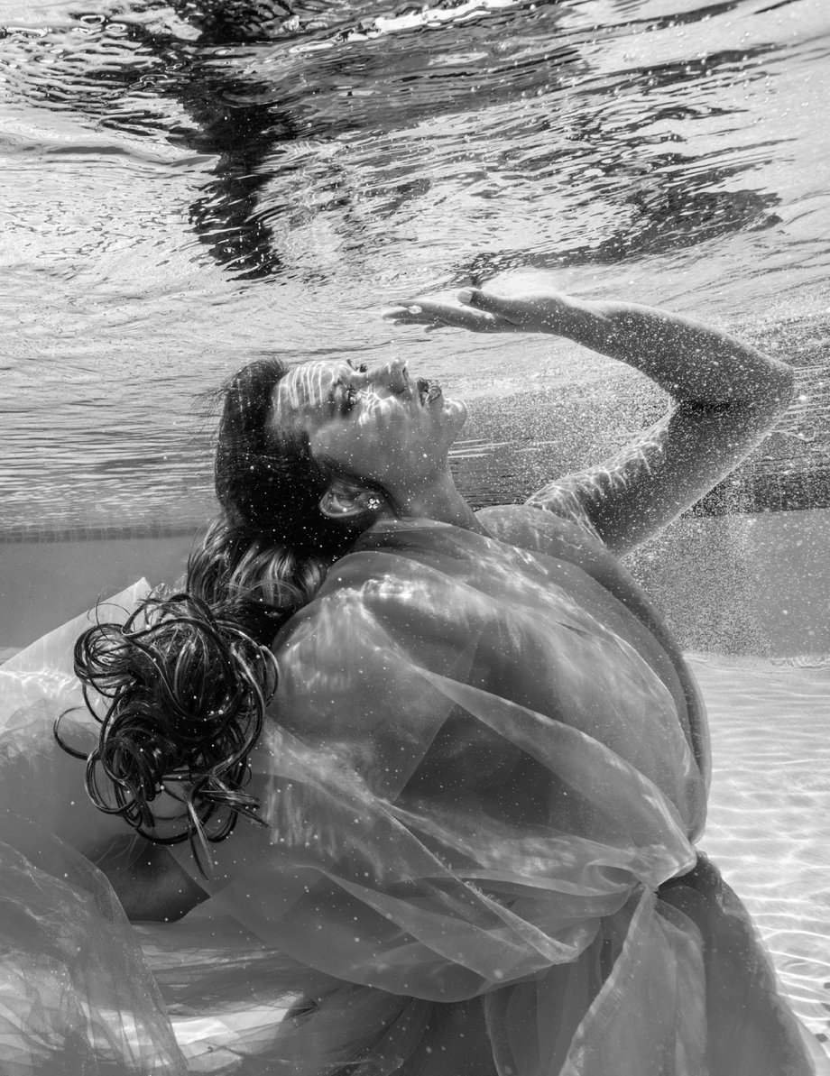 Black and white shot of Kristina Makushenko underwater with tiny bubbles streaming in shot by George Kamper for Venice magazine