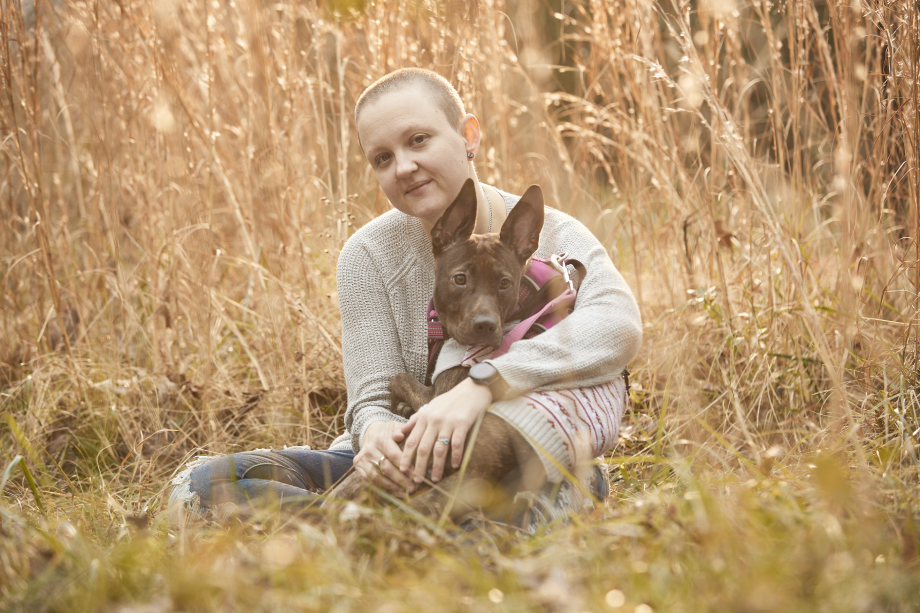 Ashley and her dog sitting in a grassy field shot by Gregory Miller for CoverMyMeds