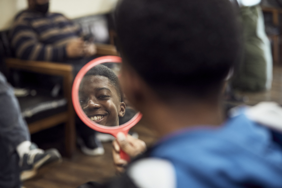 Tonia's son smiles into a mirror while getting a haircut shot by Gregory Miller for CoverMyMeds