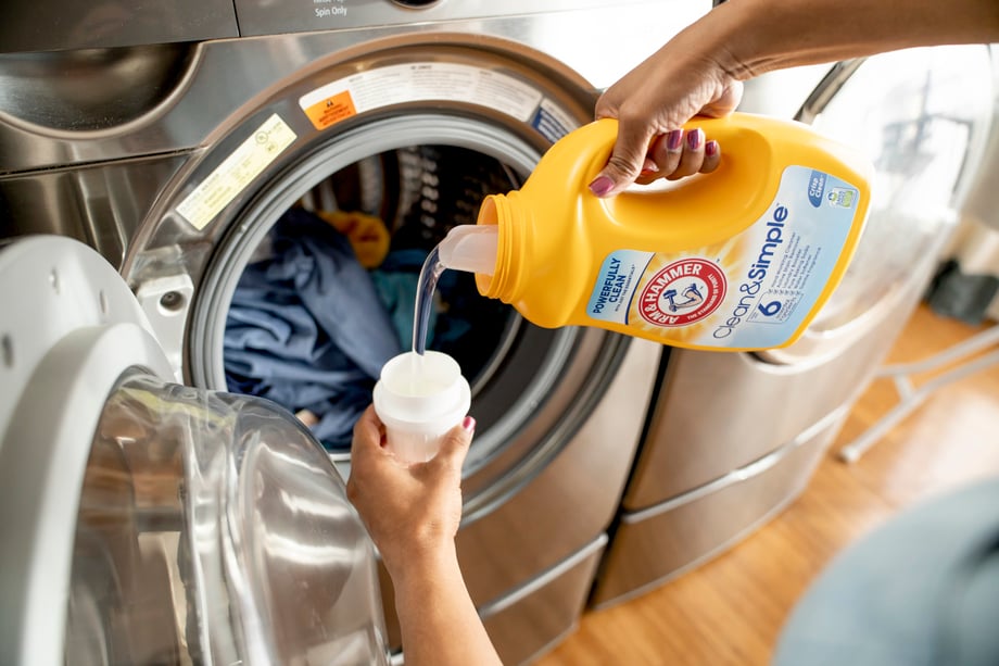 Woman pouring Arm and Hammer laundry detergent by washer shot by Inti St Clair