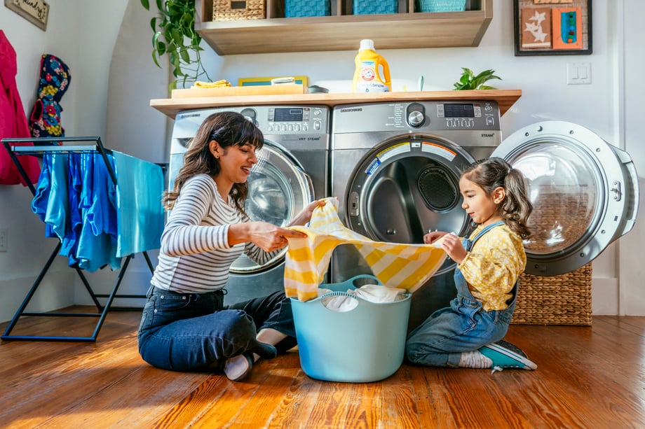 Mom and daughter folding laundry together on floor by dryer shot by Inti St. Clair for Arm and Hammer