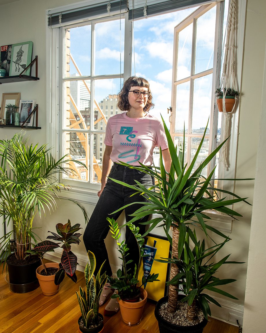 Woman standing by open window amid an abundance of plants shot by Jaime Borschuk for Women at Home project