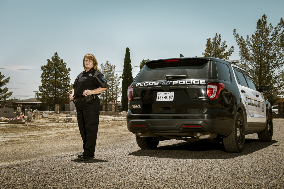 Lisa Durango standing next to her police cruiser at the Fairview cemetery shot by John Davidson for Texas Monthly