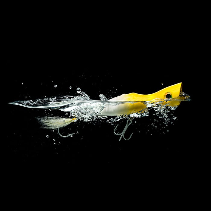 A bright yellow fishing lure half in and out of the water for Scabelly