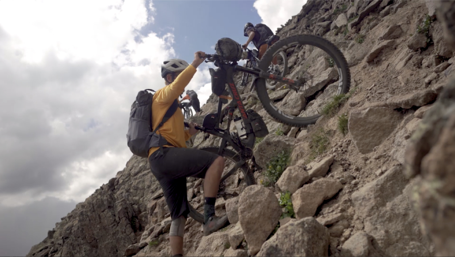One biker pushing his bike up a rocky mountain scramble from Kody Kohlman's film C-Team shot for Fat Tire