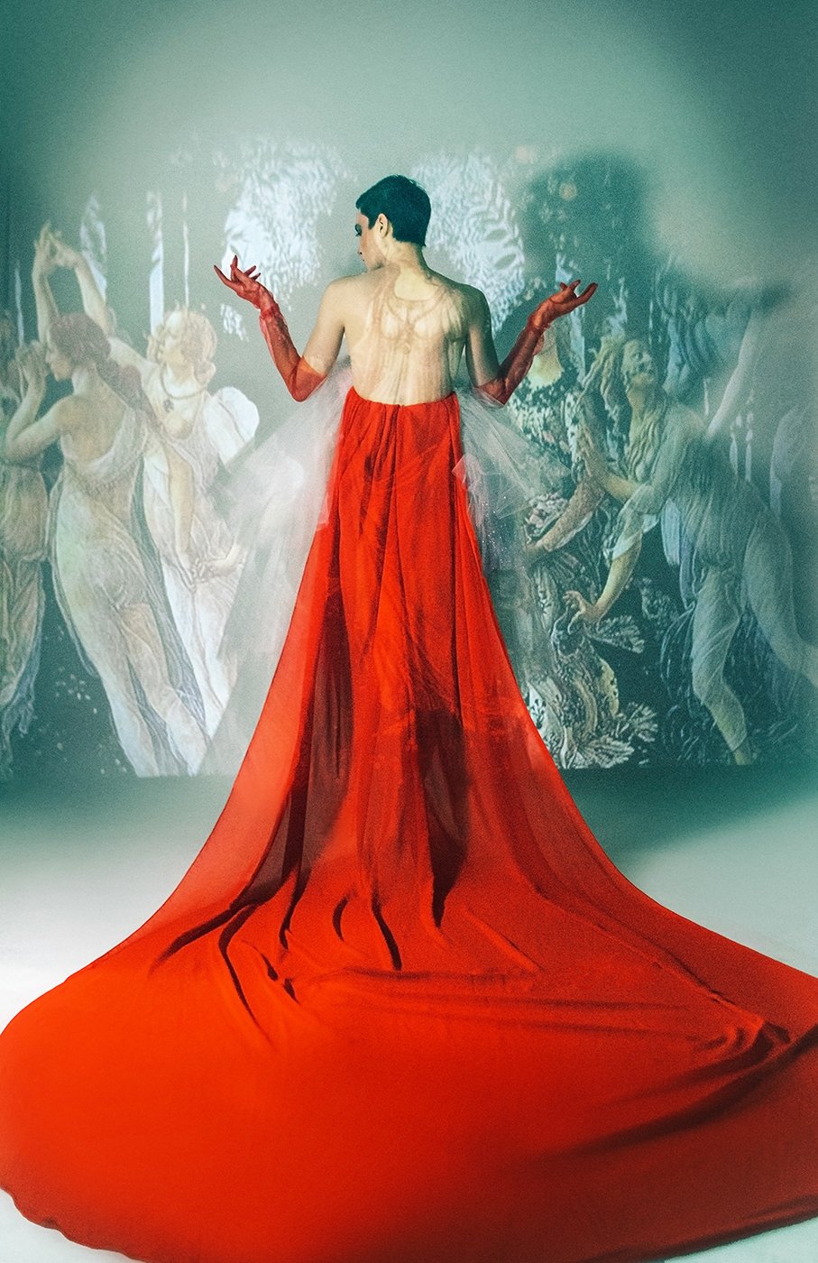 Model Amelia Pool wearing long red gown with matching red gloves standing in front projected Renaissance art shot by Kirsten Miccoli