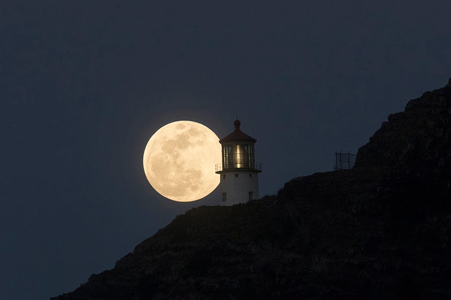 Supermoon perfectly positioned next to Makapu'u Lighthouse in Honolulu, Hawaii. Photography by Marco Garcia for Reuters. 