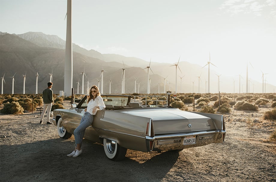 Models pose with a Cadillac convertible against windmills in the background. Photographed by Marissa Roseillier for American Optical. 