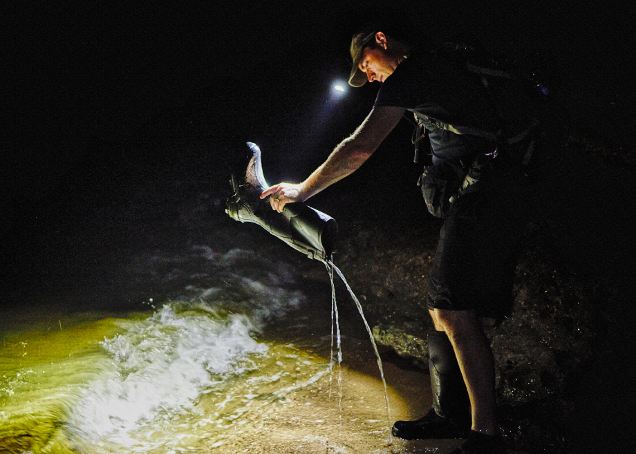 Fossil hunter pouring water out of his shoe at night for Matthew Rakola's "My Former Future Self"