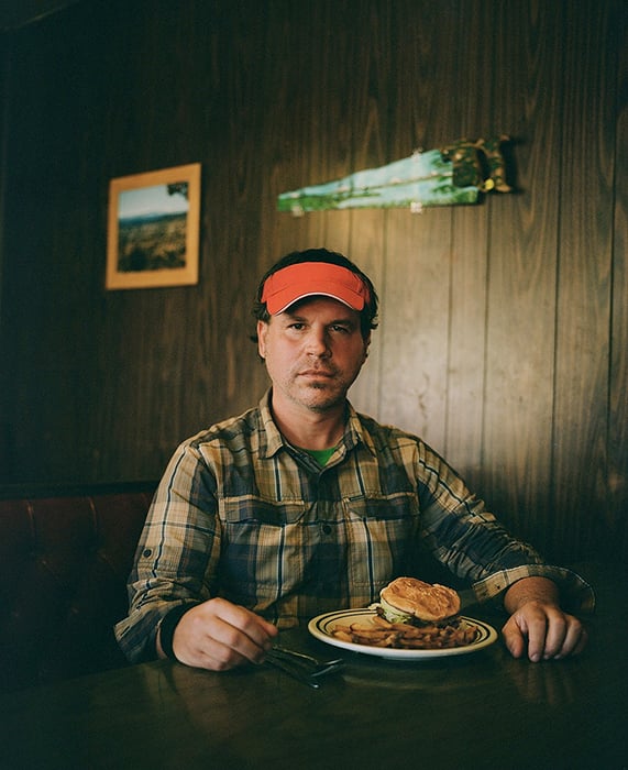 Rue McKenrick stares directly at the camera while sitting at a diner in Bend, Oregon. Photographed by Michael Hanson for Backpacker Magazine.