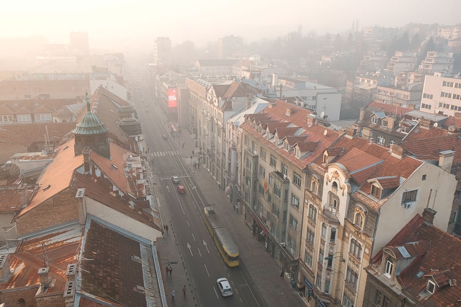 Smog hangs in the distance of Sarajevo in this view down Maršala Tita street in the city center. Photography by Nick St. Oegger. 