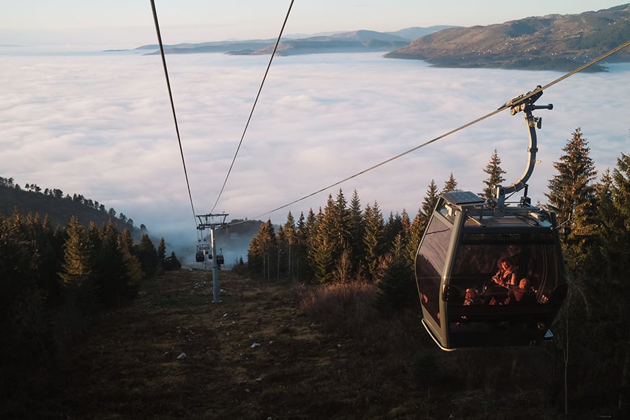 People ride a cable car up Mt. Trebević as Sarajevo is obscured by a layer of fog and pollution. Temperature inversion, which occurs when air at high altitudes becomes warmer than the air below, often keeps smog trapped in the city below. Photography by Nick St. Oegger. 