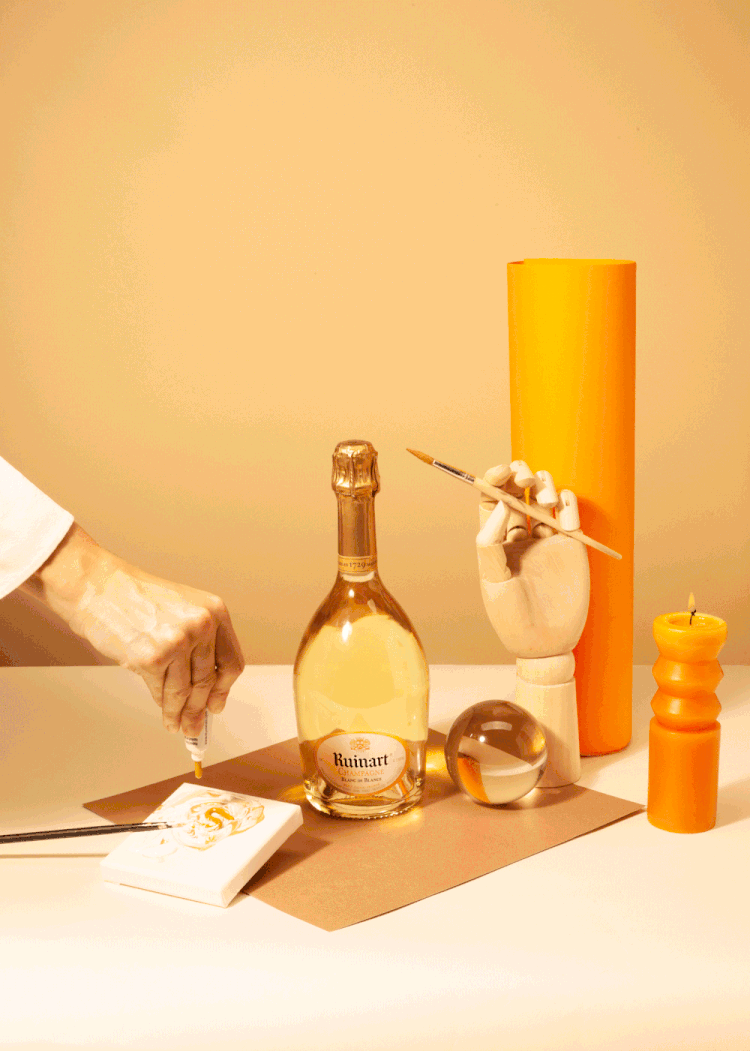 Marzia Gamba's GIF for Ruinart showing a hand squeeze and paint gold paint onto a canvas beside a champagne bottle and other props