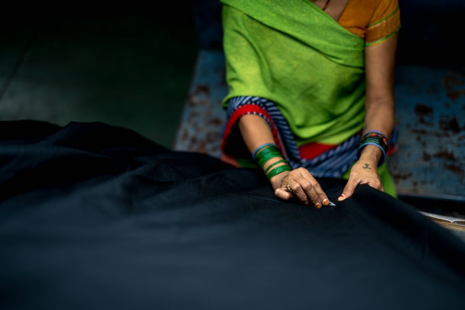 A worker sews a garment at a factory. Photography by Tim Gerard Barker. 