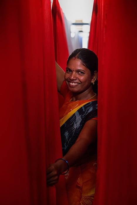 A female Zilingo employee in a factory in India smiles for the camera. Photography by Tim Gerard Barker. 