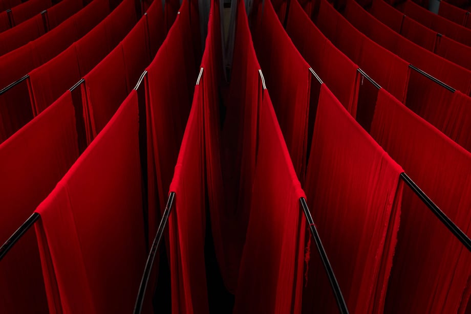 A sea of dyed red fabric hangs to dry in a factory in India. Photography by Tim Gerard Barker. 