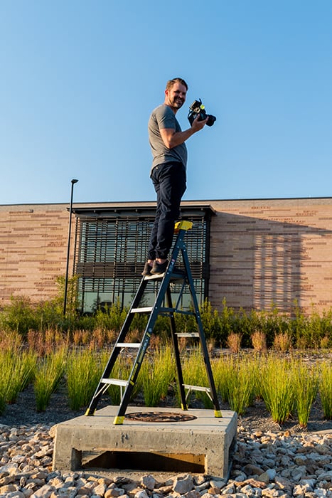 Wade Griffith on a ladder photographing the exterior of the building. Photography by Anna Boling. 