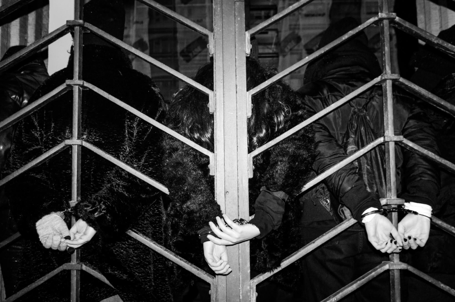 Three people handcuffed to a gate at Warsaw protests shot by Wojciech Grzedzinski for Republik Magazine