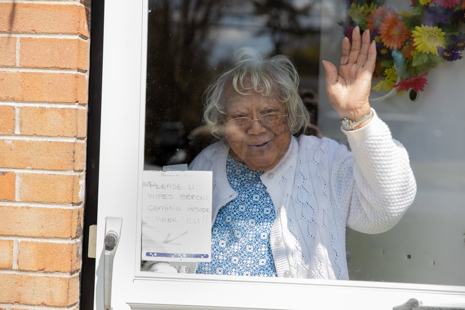 Photo of a woman waving through door after receiving her meal.