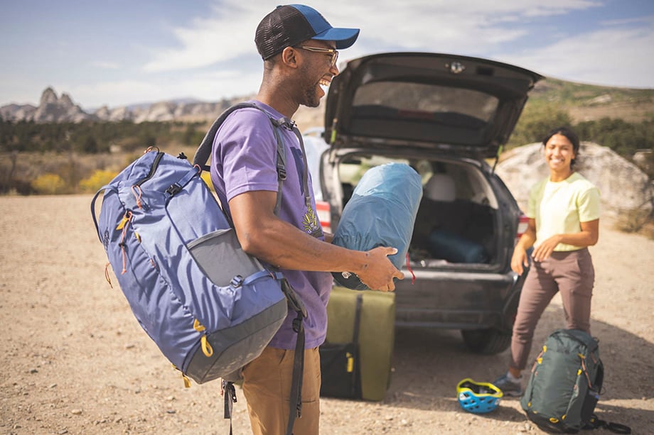 Chey Smith and Steven Frederick in front of car with camping equipment shot by D. Scott Clark