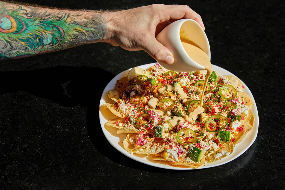 Andrea's favorite photo shows a beautiful and unique plating of nachos with cheese being poured by the chef's tattooed arm