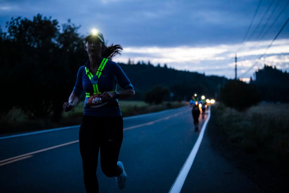 Photo of Hood To Coast runners at night wearing headlights as they run down the side of a road.