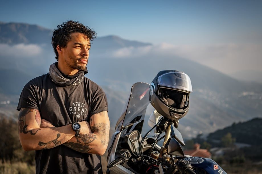 Alex Buisse's photo of a man standing next to his motorcycle in front of a mountain range for Garmin 
