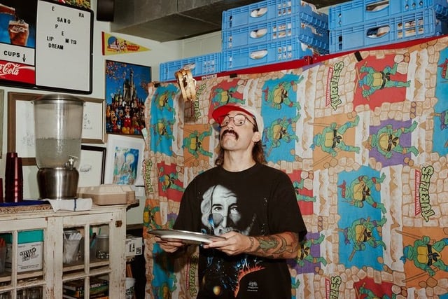 Tim Black approached Wonderful Machine to help him find a rep. This image of a tattooed, mustachioed chef (Mason Hereford) is exemplary of Tim's photographic style and background. Mason is seen flipping a sandwhich in the air (to hopefully land back on the plate that he is holding). The background is an eclectic mix of vintage Teenage Ninja Mutant Turtles bedspread and other quirky items.