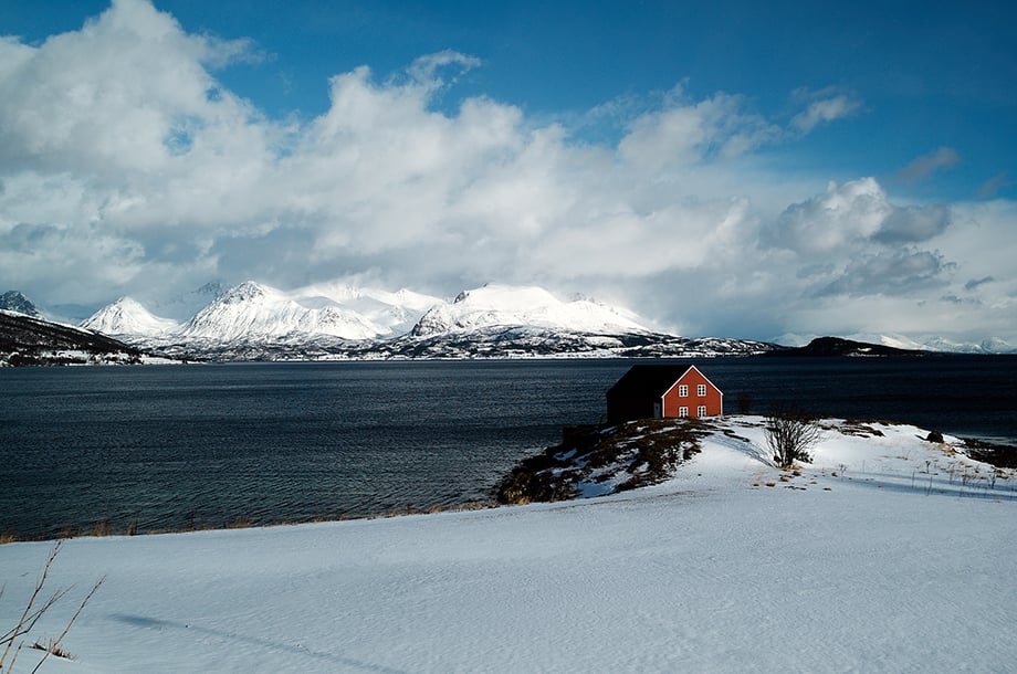 House on island with mountain backdrop by Øivind Haug