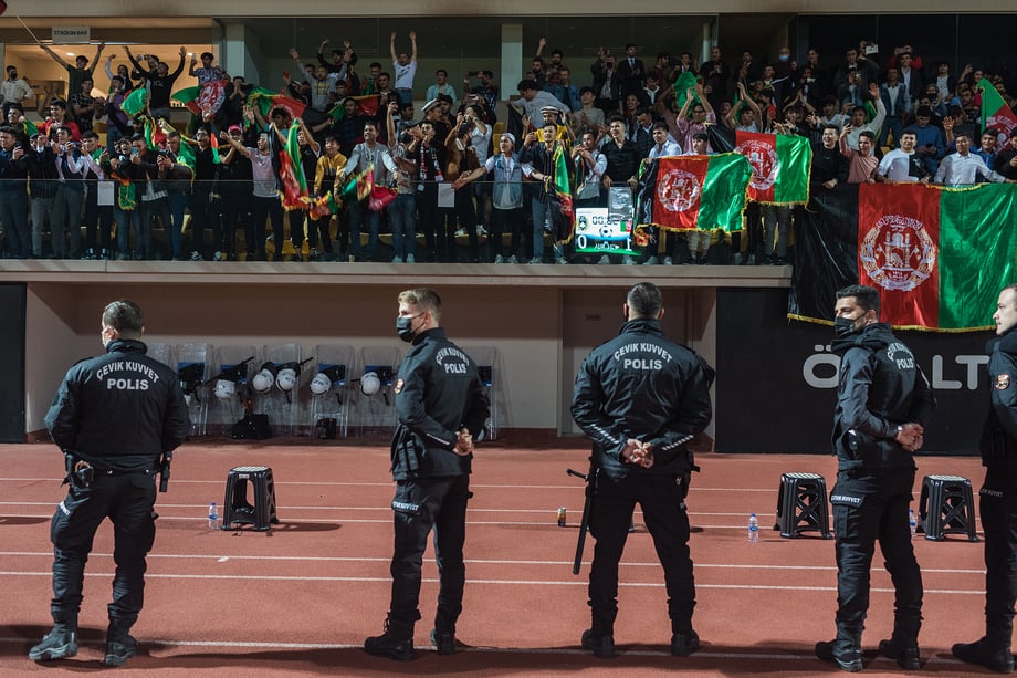 Afghan fans cheering at the soccer stadium in Antalya, Turkey, where the Afghanistan National Soccer team won an international friendly match with Indonesia. Turkish police stand between the fans and the soccer players. Shot by Bradley Secker for the New York Times.