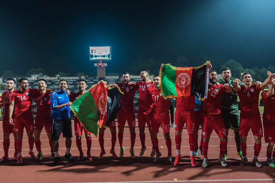 The Afghan national team celebrate a 1-0 victory against Indonesia in the team's first match since the Taliban took control of Afghanistan. They raise the pre-Taliban Afghanistan national flag. Shot by Bradley Secker for the New York Times.