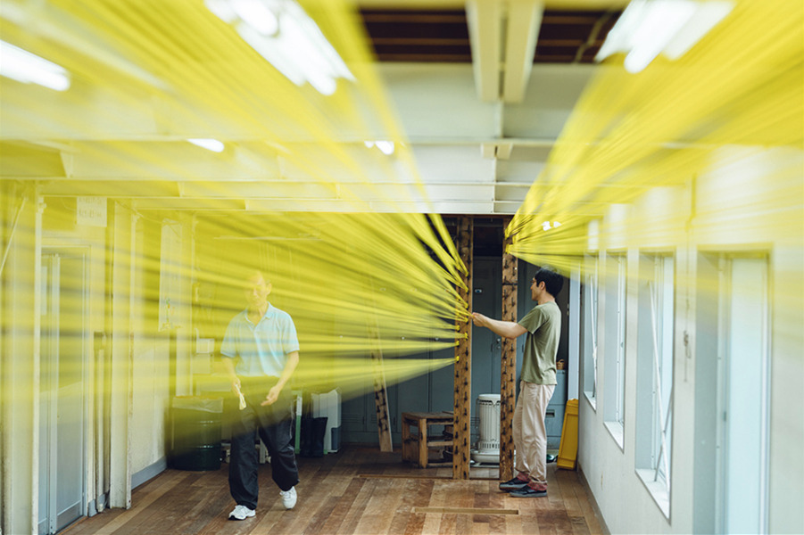 Artists use yellow string to create design, captured by Tokyo-based artisanal photographer Irwin Wong.