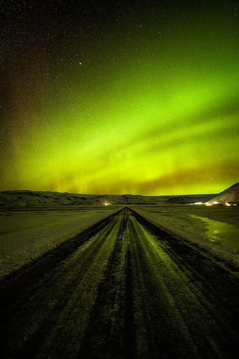 The Aurora Borealis over a road in Iceland taken by landscape photographer Rachid Dahnoun.