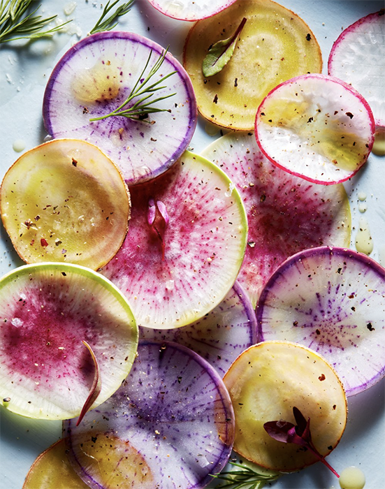 Thinly sliced root vegetables arranged on a tabletop by NYC-food photographer Ghazalle Badiozamani.