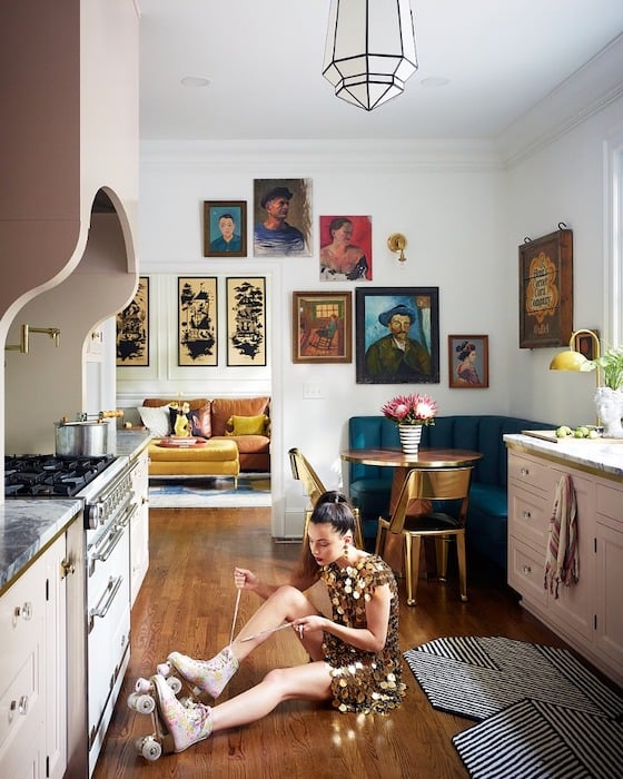 Portrait of a woman putting on roller skates in a pink kitchen shot by interior and portrait photographer Chris Edwards.