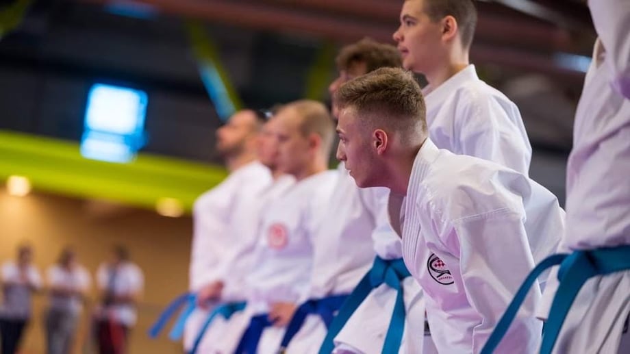 Side profile of karate champion Mihael Ećimović standing in a line with competitors.