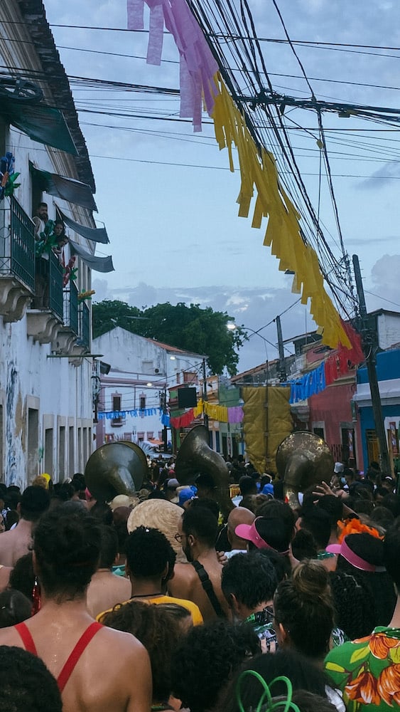 Street-view of brass musicians walking in crowd at Carnival celebration.