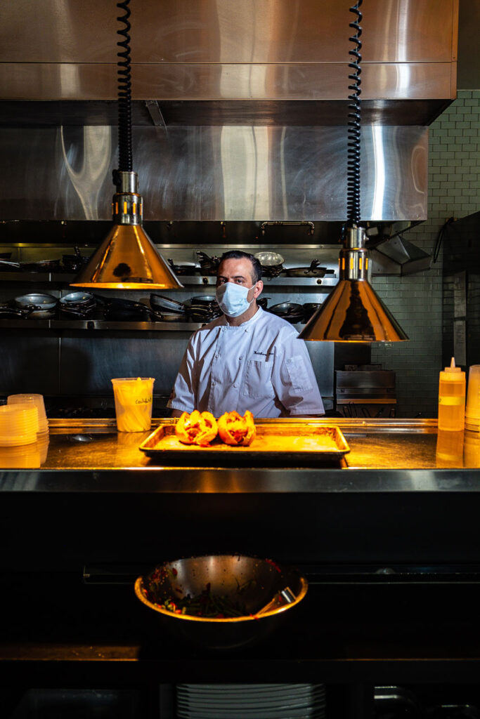 Photo by Andrew Dolph of chef Matt Mytro in the kitchen with two sandwiches right out of the oven.