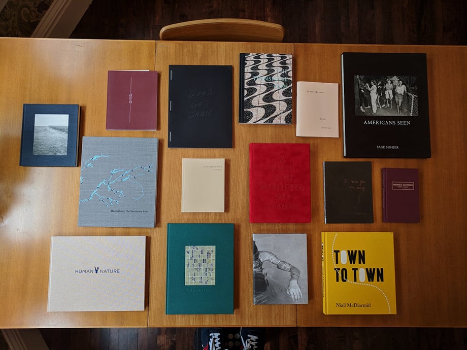 A selection of Andy Adams' books from independent photobook publishers laid on a tabletop.