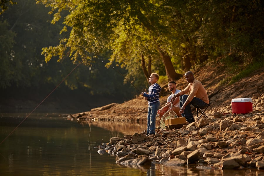 Two fathers smile as their son fishes in a woodsy lake by photographer Clay Cook of Louisville, Kentucky. 